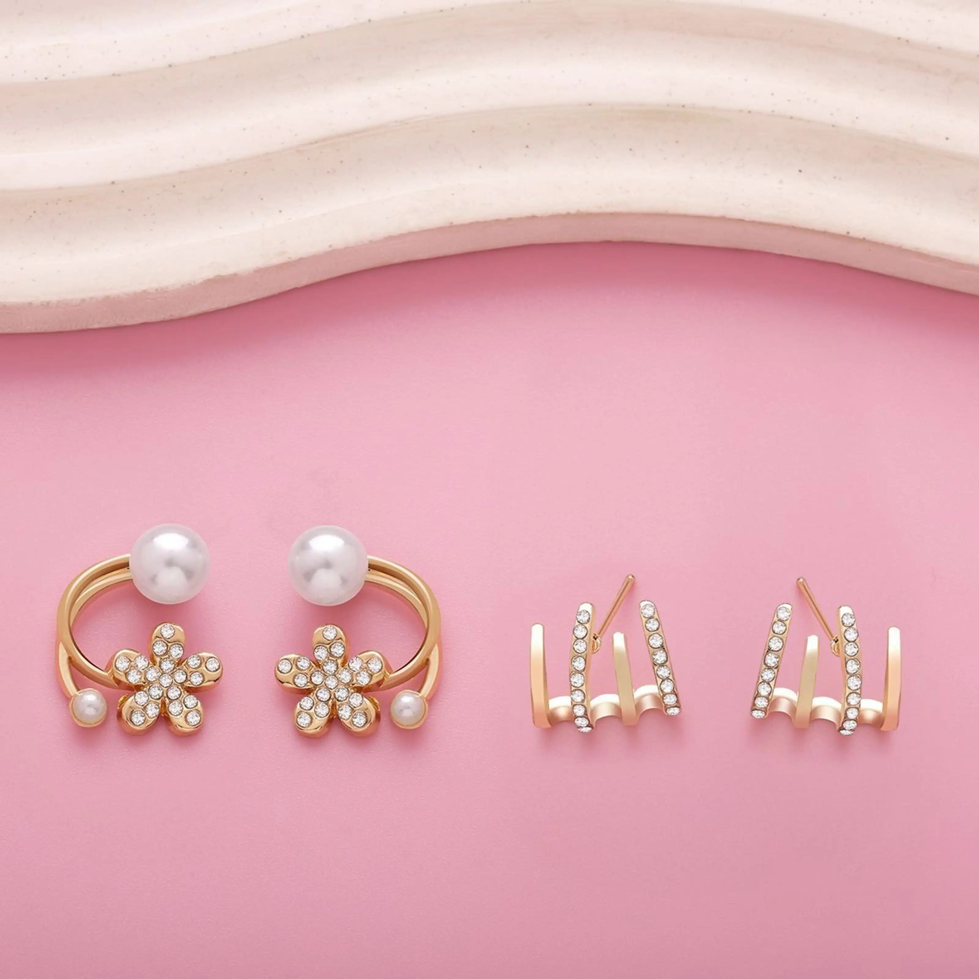 dazzle21 gold-tone daisy flower earrings with faux pearls and crystal studs on a pink background