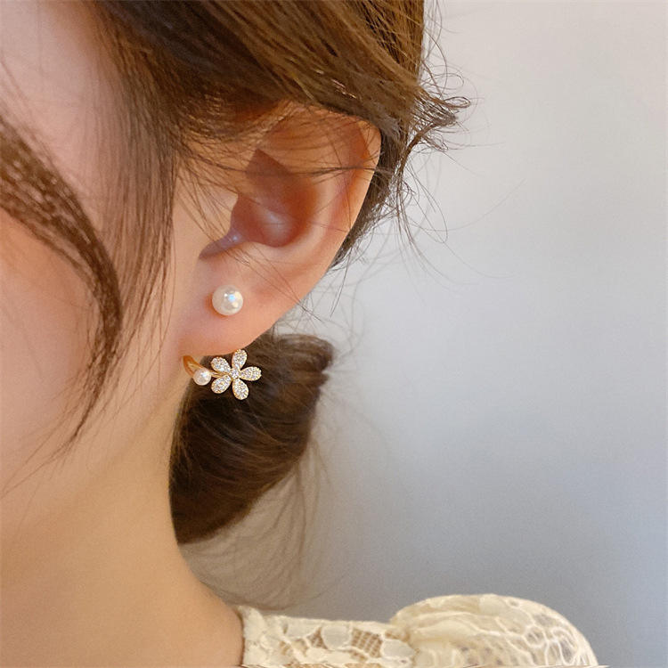 dazzle21 gold-tone daisy ear jacket earrings with micro-crystals and faux pearls worn on a woman's earlobe