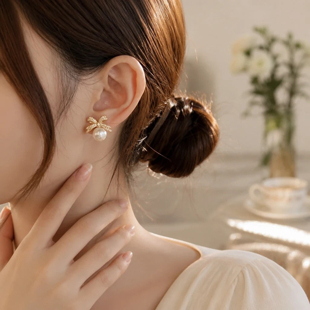 dazzle21 gold-tone bow stud earrings with a lustrous faux pearl and cubic zirconia accents worn on a woman's ear