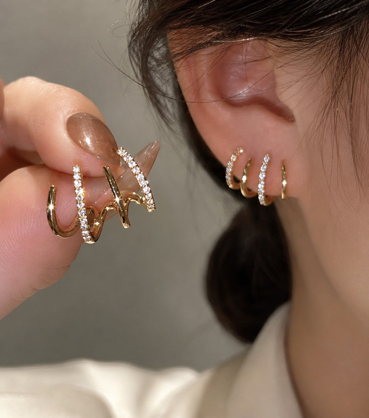 dazzle21 gold-tone multi-hoop earrings with cubic zirconia accents worn on ear and held by fingers