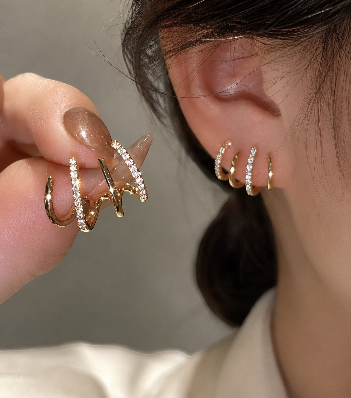 dazzle21 gold-tone multi-hoop earrings with cubic zirconia accents worn on ear and held by fingers