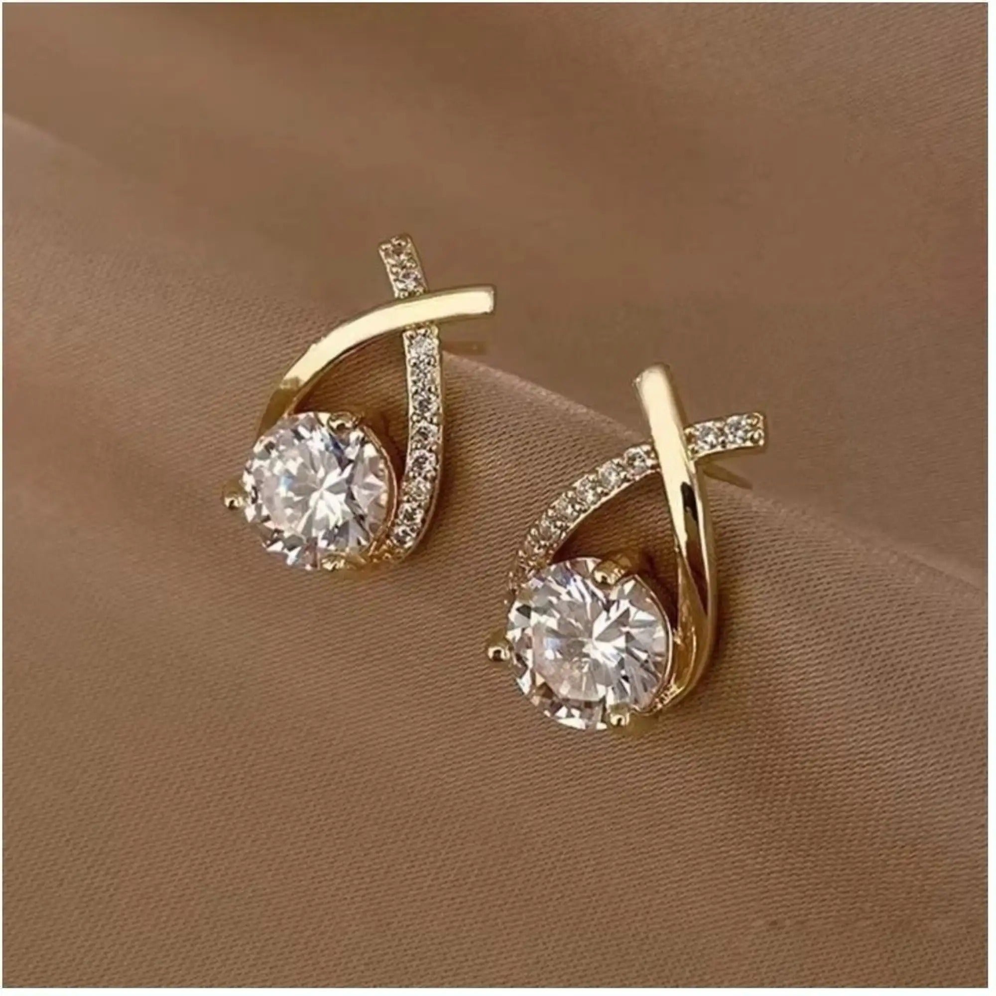 dazzle21 gold-tone stud earrings featuring a cross-over design with a central cubic zirconia stone and pavé accents