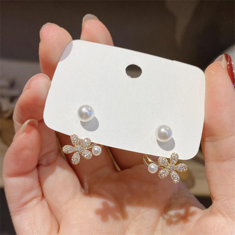 dazzle21 gold-tone daisy ear jacket earrings with micro-crystals and faux pearls held in a hand