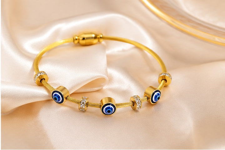 dazzle21 gold-tone wire bracelet featuring blue evil eye nazar charms and sparkling crystal accents on satin fabric