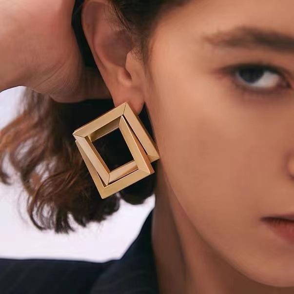 dazzle21 geometric square statement earrings in polished gold-tone metal worn by a model