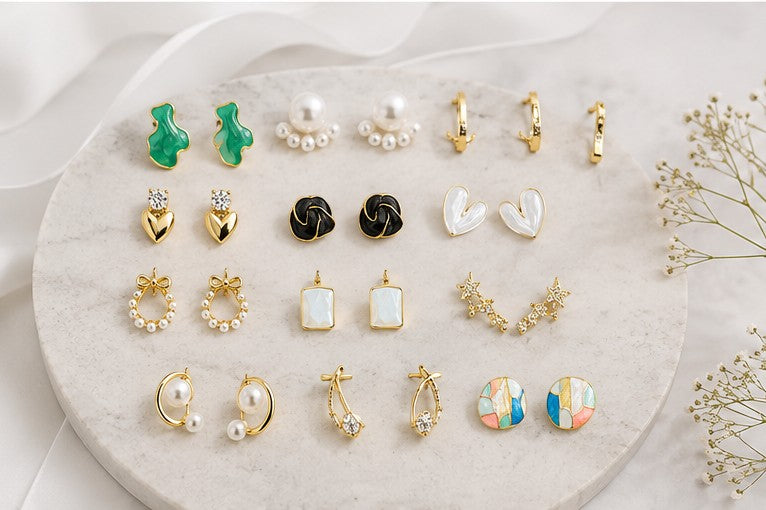 dazzle21 12-pair fashion earring set featuring gold-tone, pearl, heart, and statement designs on a stone display tray.