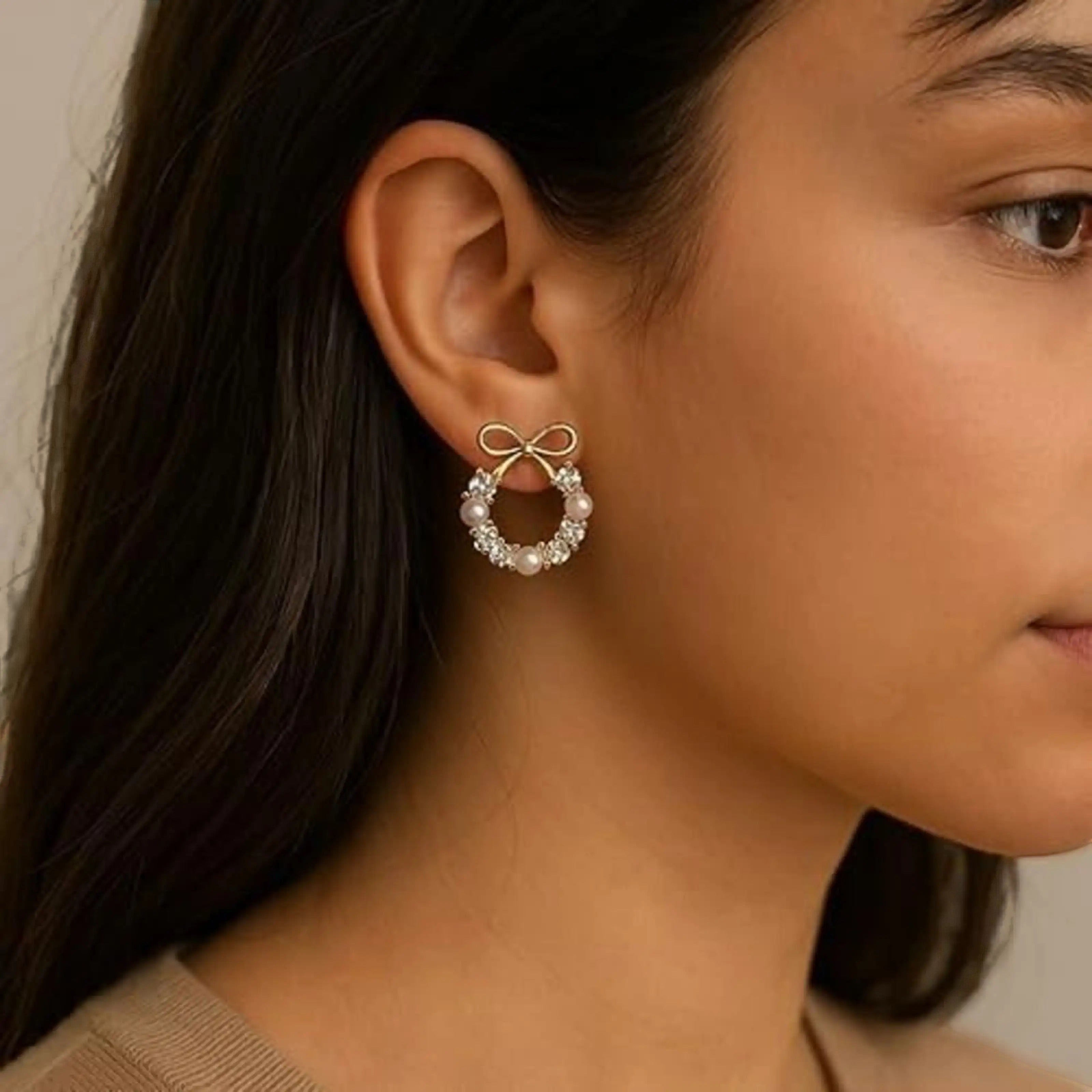 dazzle21 gold plated wreath earrings featuring a delicate bow, pearls, and sparkling cubic zirconia on a model