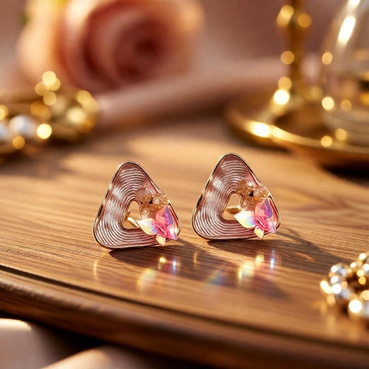 dazzle21 gold geometric triangle stud earrings with peach pearls and iridescent butterfly accents on a wooden table