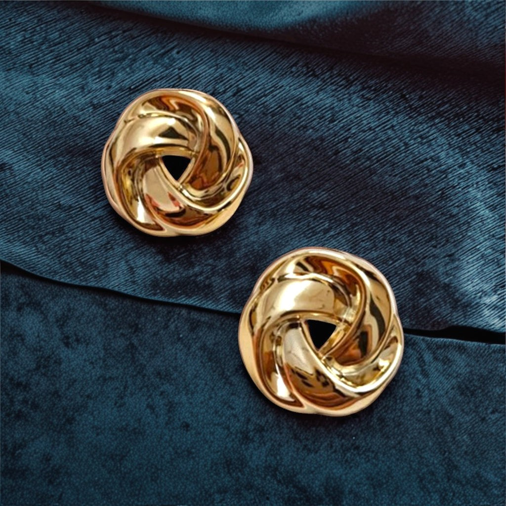 dazzle21 twisted knot earrings in polished gold finish resting on a dark blue velvet fabric background