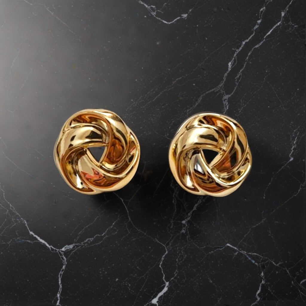 dazzle21 twisted knot earrings in polished gold finish on a black marble surface