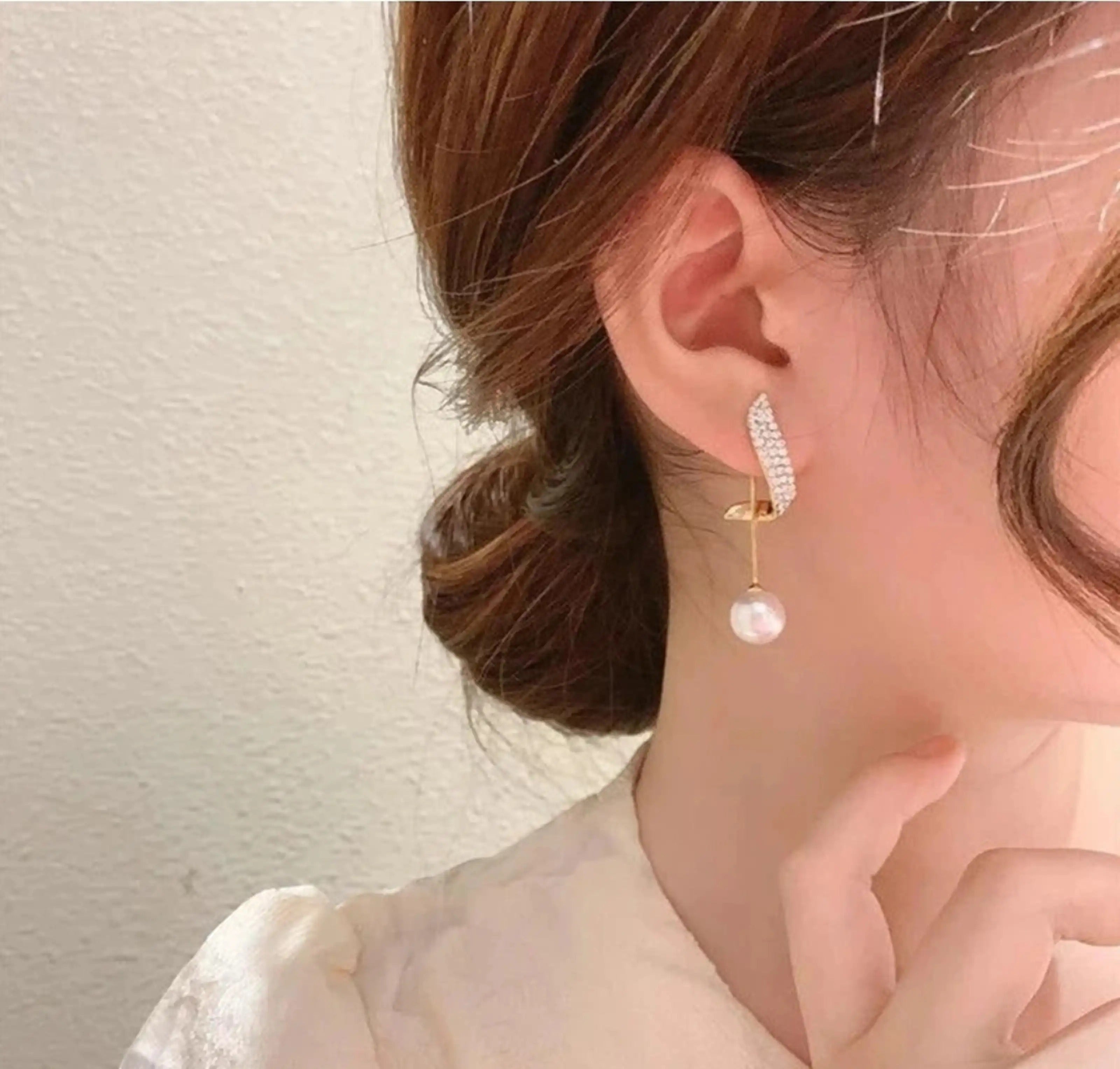 dazzle21 korean style gold alloy stud earrings with zircon crystals and a dangling pearl worn by a woman