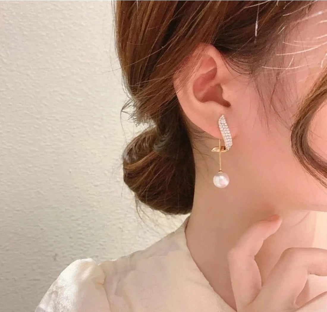 dazzle21 korean style gold alloy stud earrings with zircon crystals and a dangling pearl worn by a woman