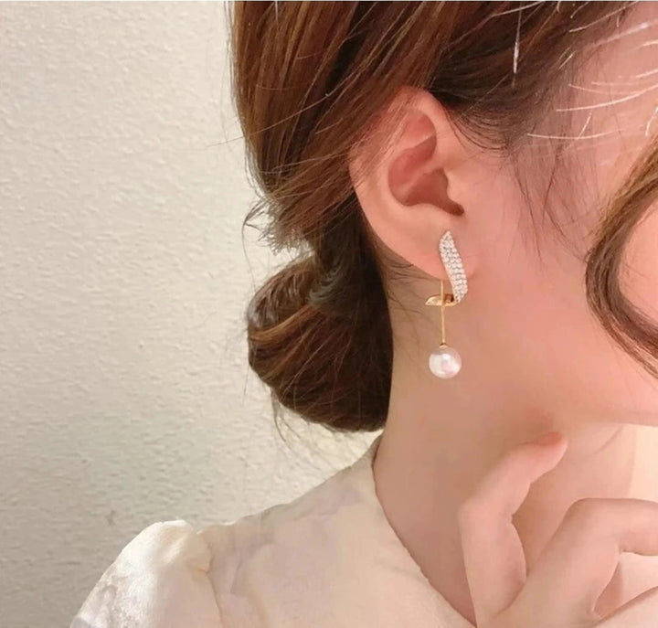 dazzle21 korean style gold alloy stud earrings with zircon crystals and a dangling pearl worn by a woman