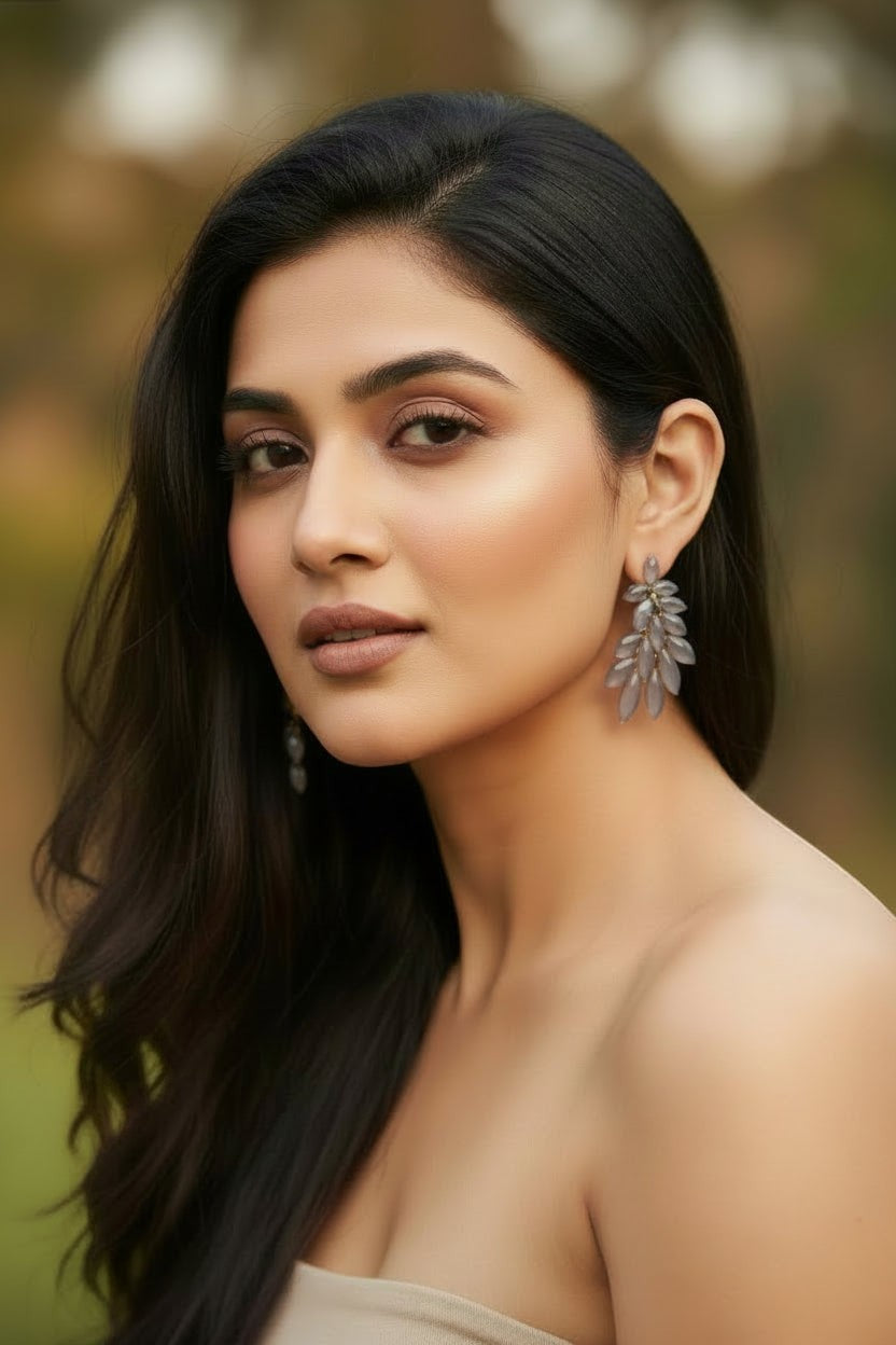 dazzle21 golden leaf statement stud earrings with crystal accents worn by a woman with long dark hair