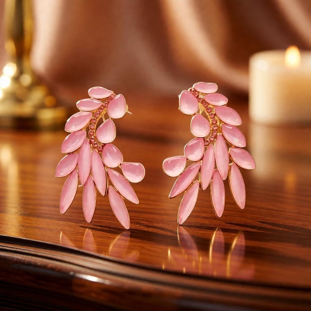 dazzle21 golden leaf stud earrings featuring light pink petal-shaped stones and crystal accents on a wooden table.