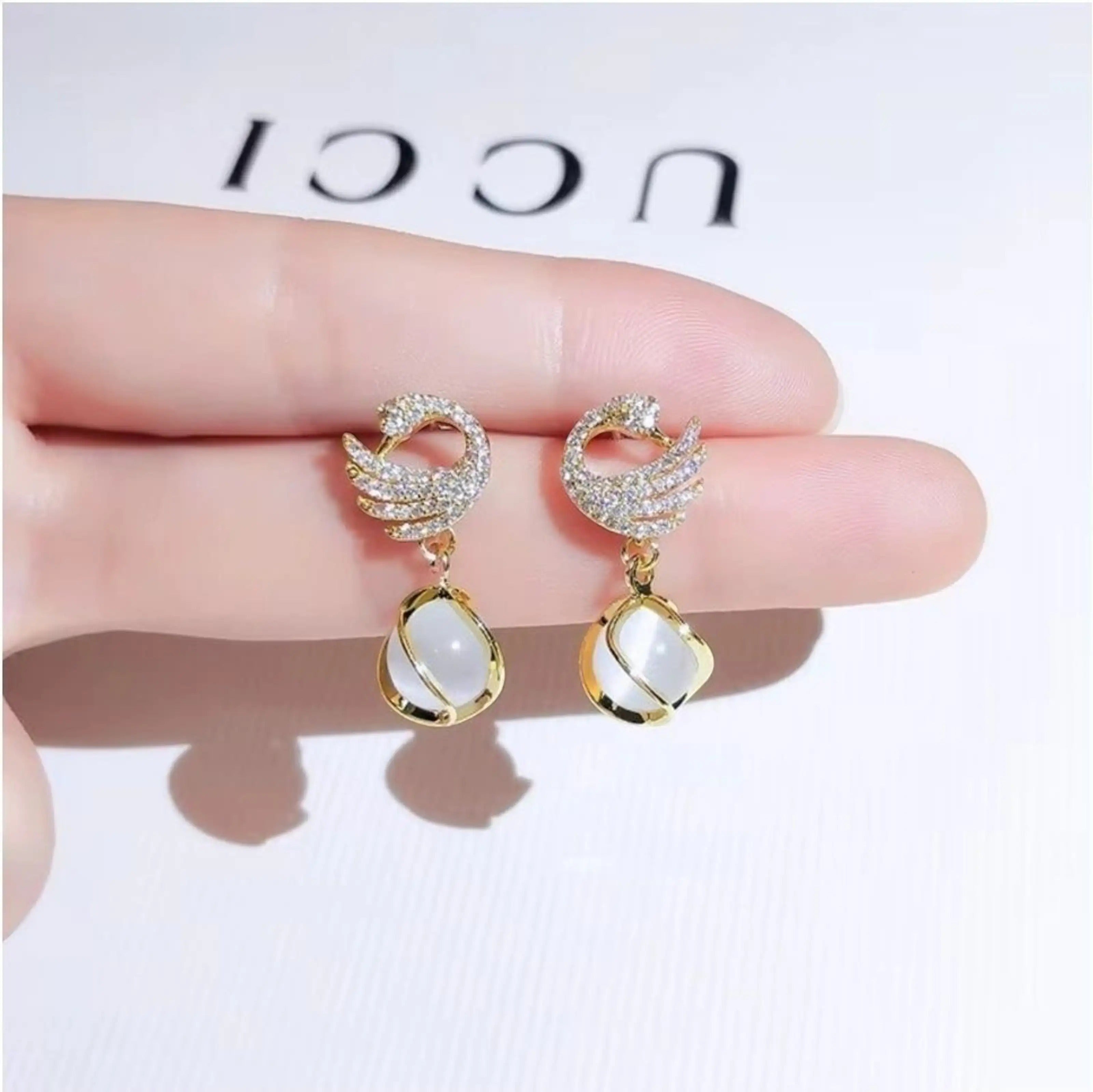 dazzle21 golden swan-shaped stud earrings with sparkling cubic zirconia and dangling white opal-style stones