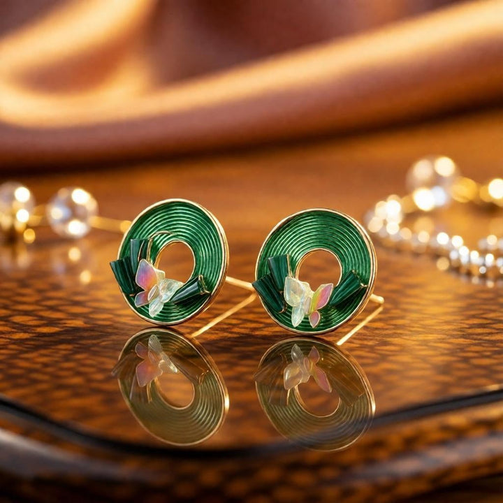 dazzle21 green circular spiral stud earrings with delicate pastel butterfly accents on a reflective surface