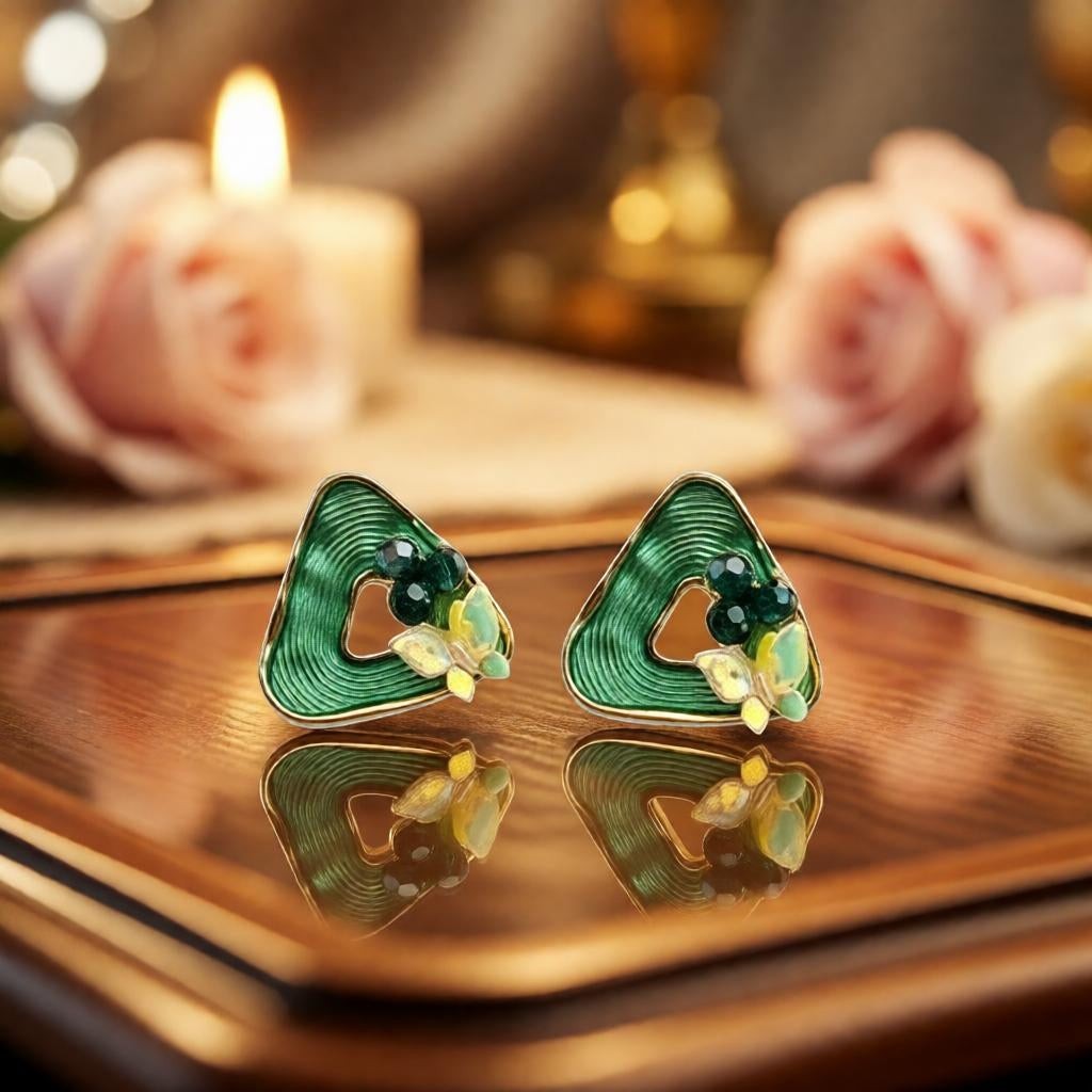 dazzle21 triangular ribbed stud earrings in green with butterfly and pearl accents on a reflective surface