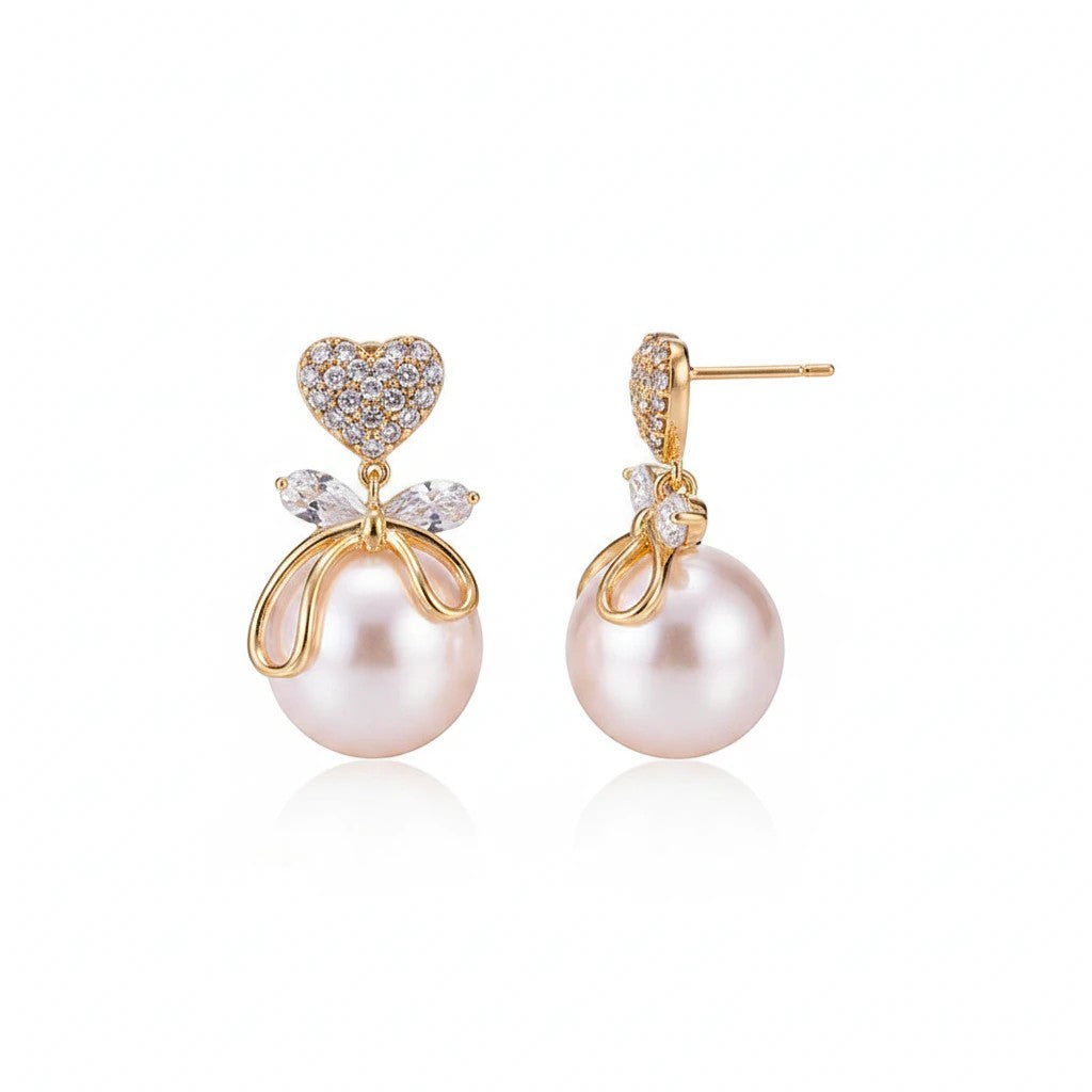 dazzle21 Luxe Heart Pearl Bow Drop Earrings featuring crystal heart studs, gold bows, and lustrous faux pearl drops.