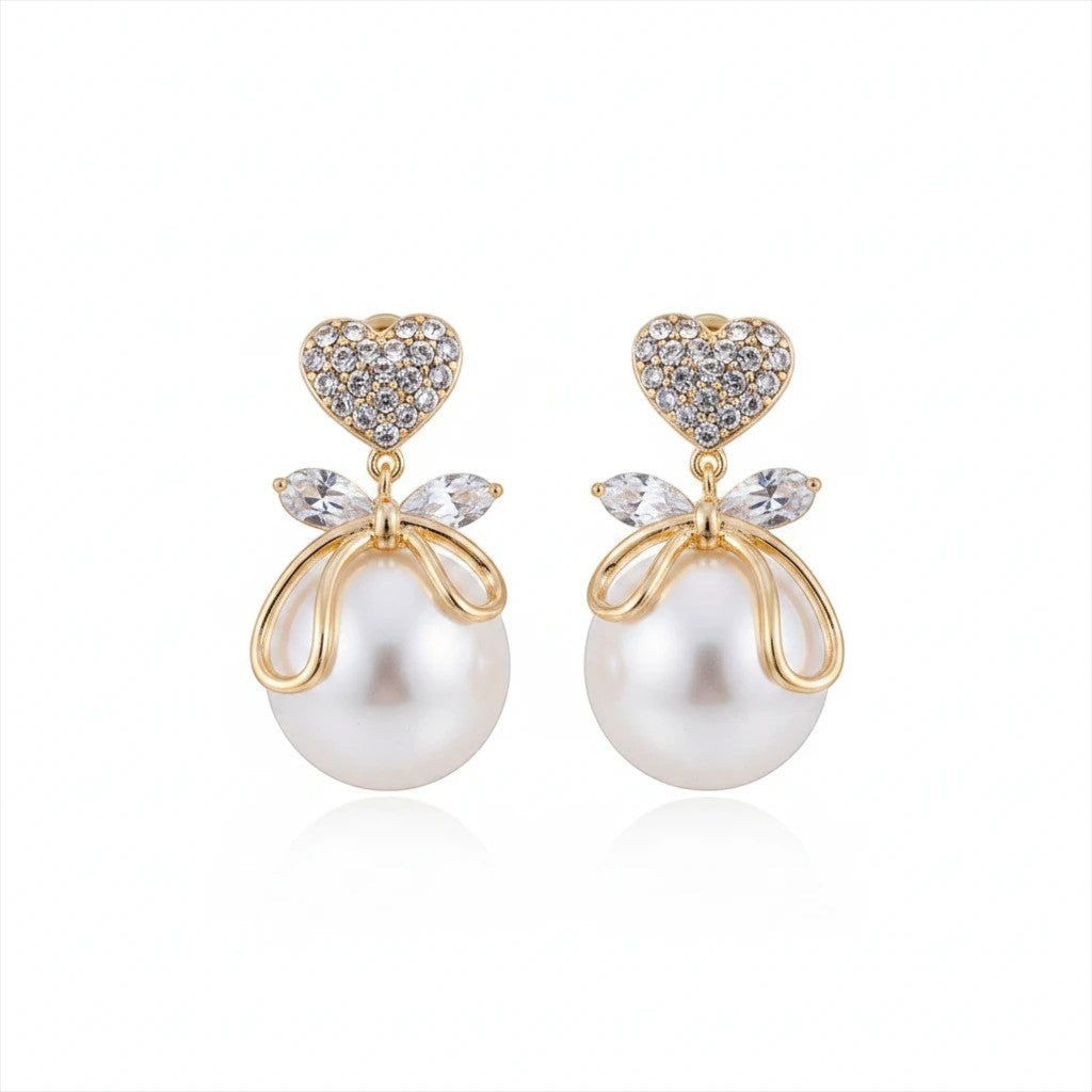 dazzle21 gold heart crystal stud earrings with bow detail and lustrous faux pearl drop on a white background