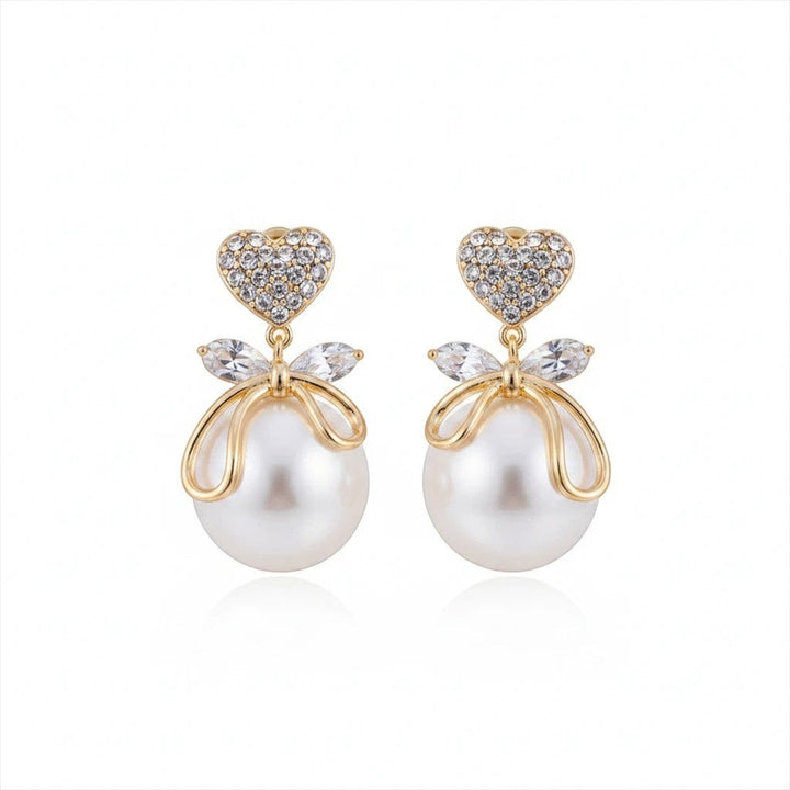 dazzle21 gold heart crystal stud earrings with bow detail and lustrous faux pearl drop on a white background