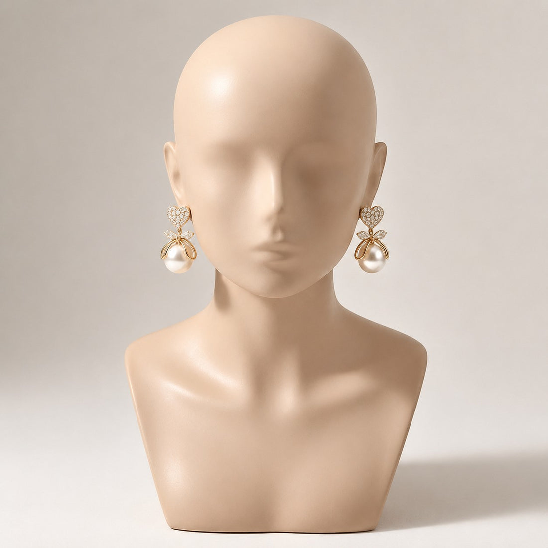 dazzle21 gold-tone heart-shaped pearl earrings with crystal accents on a mannequin bust