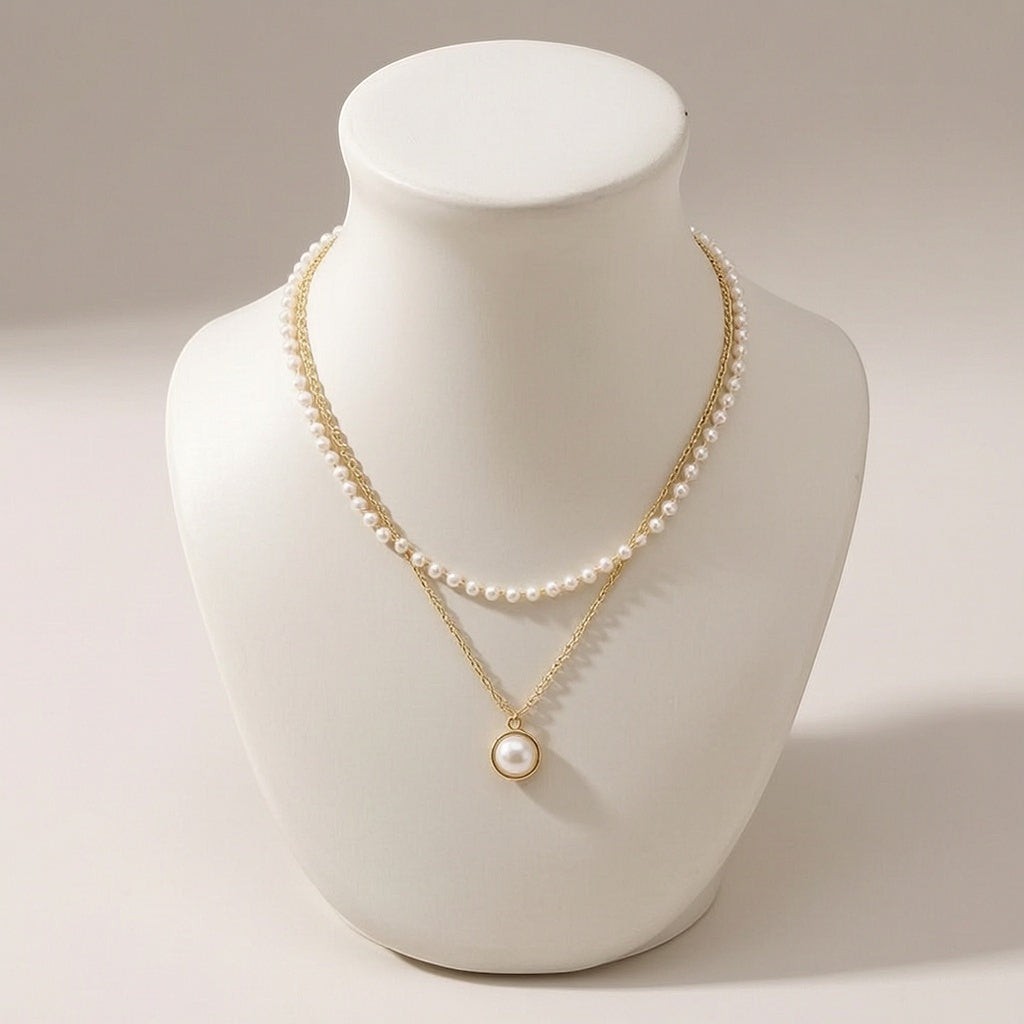 dazzle21 layered gold chain necklace with small white pearls and a central pearl pendant on a display bust