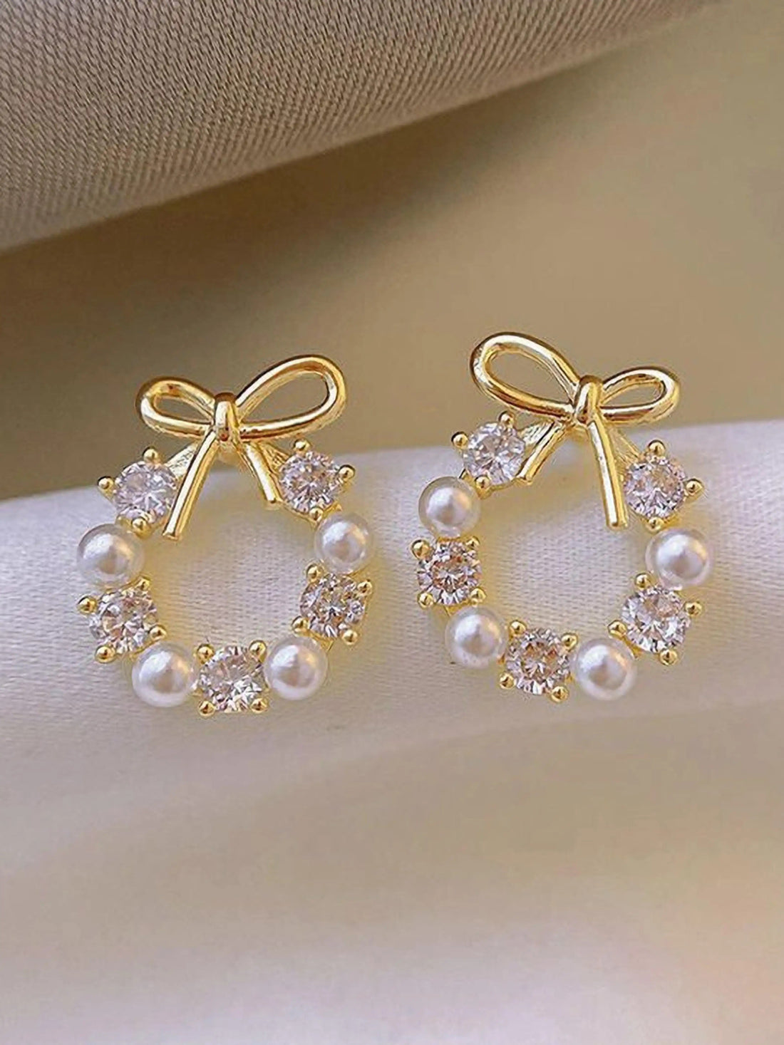 dazzle21 gold-tone bow earrings featuring a circular wreath design with alternating white pearls and clear crystals