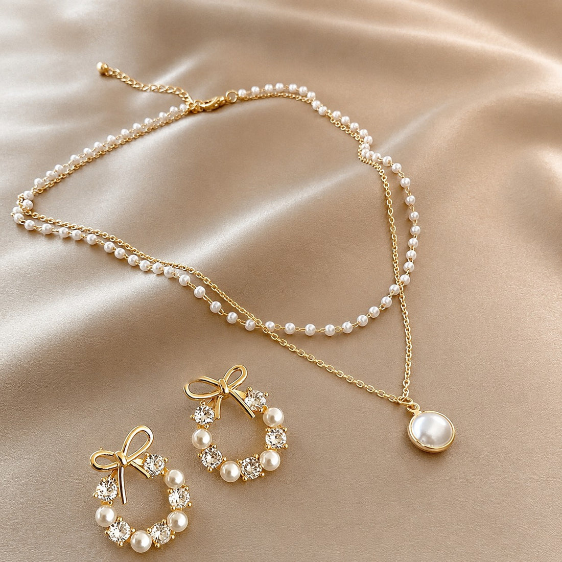 dazzle21 gold-tone jewelry set featuring a double-layer pearl necklace with pendant and bow-shaped crystal pearl earrings