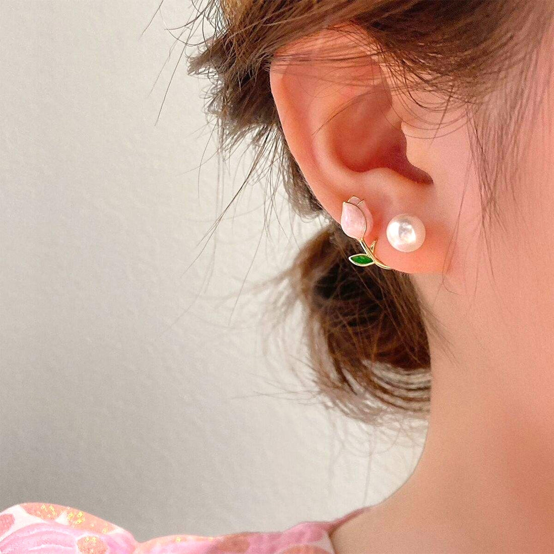 dazzle21 gold-tone ear cuff earrings featuring a pink tulip, green leaf, and faux pearl worn on a woman's ear