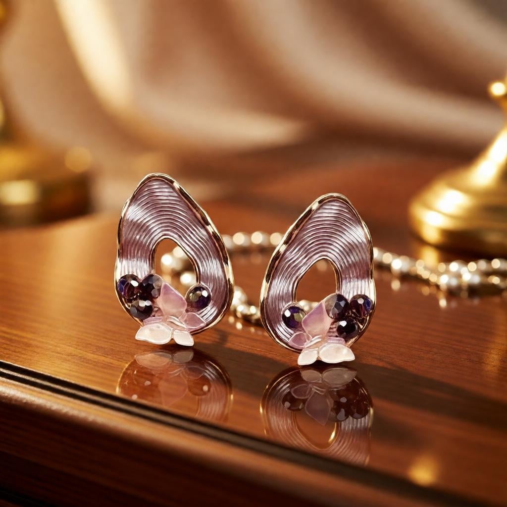 dazzle21 pear-shaped ribbed gold earrings with butterfly accents and purple pearls on a polished wooden surface