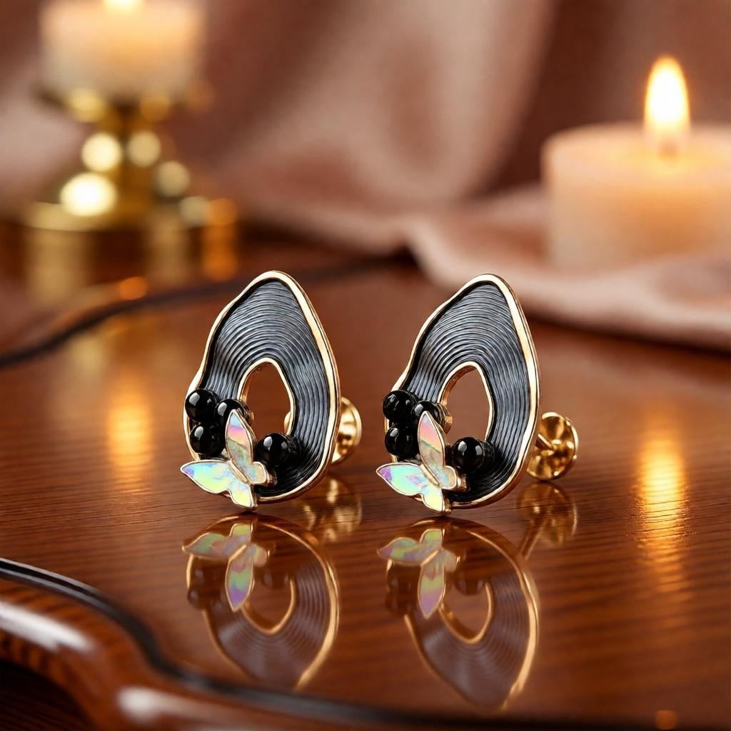 dazzle21 pear-shaped ribbed earrings with black enamel, pearl accents, and iridescent butterfly charms on wood table