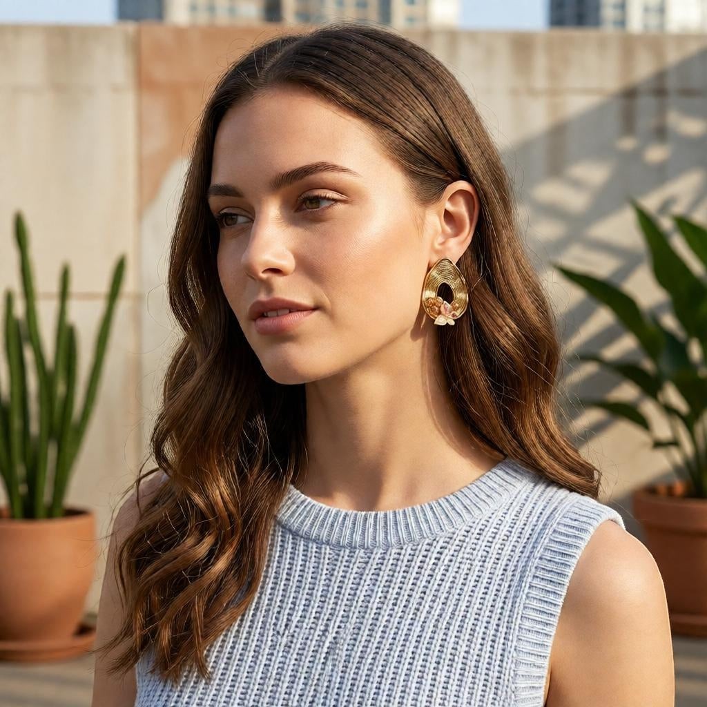 dazzle21 pear-shaped ribbed gold teardrop earrings with pearl and butterfly accents worn by a woman