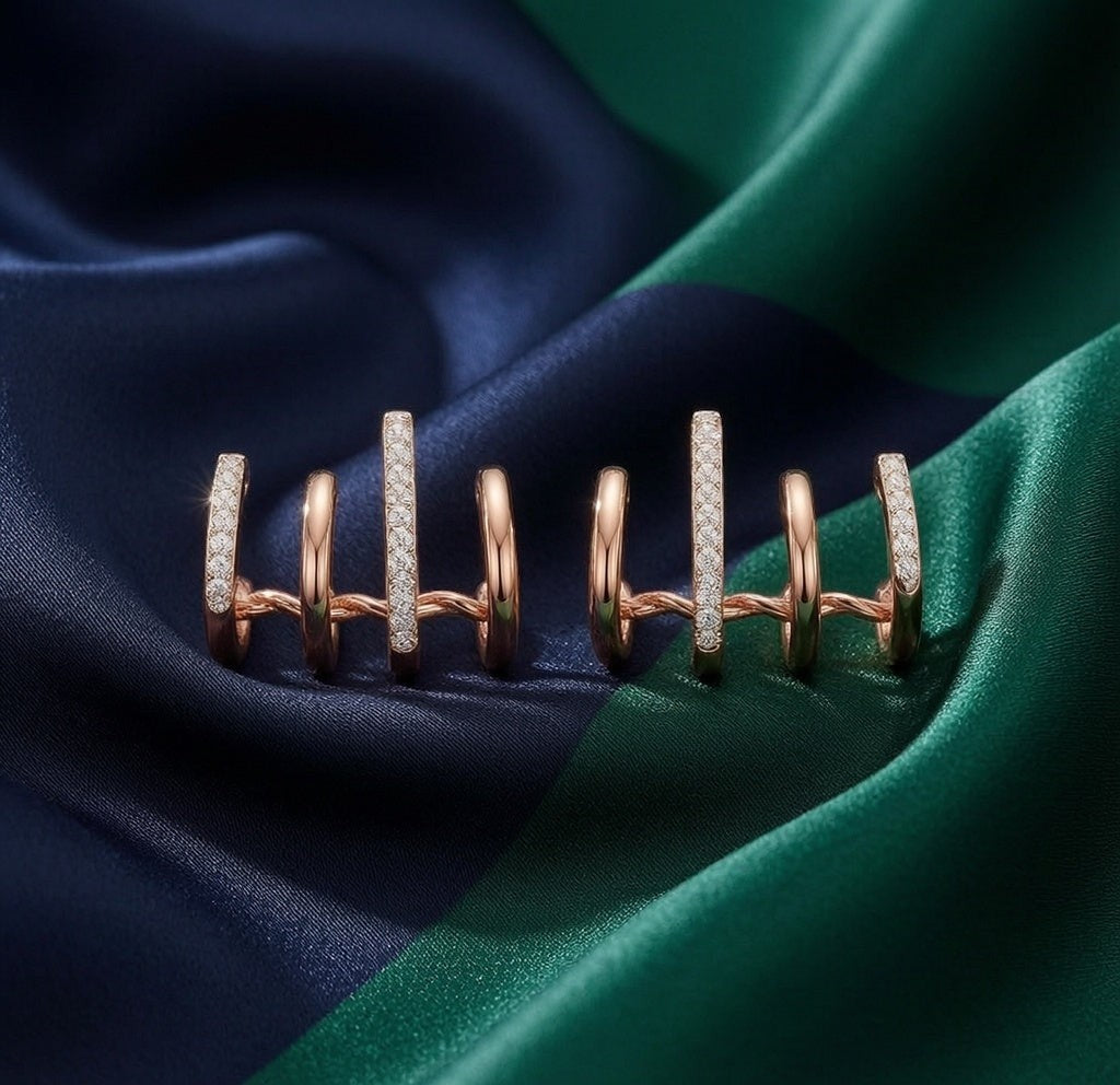 dazzle21 rose gold claw-style earrings with cubic zirconia accents on a dark blue and green silk fabric background