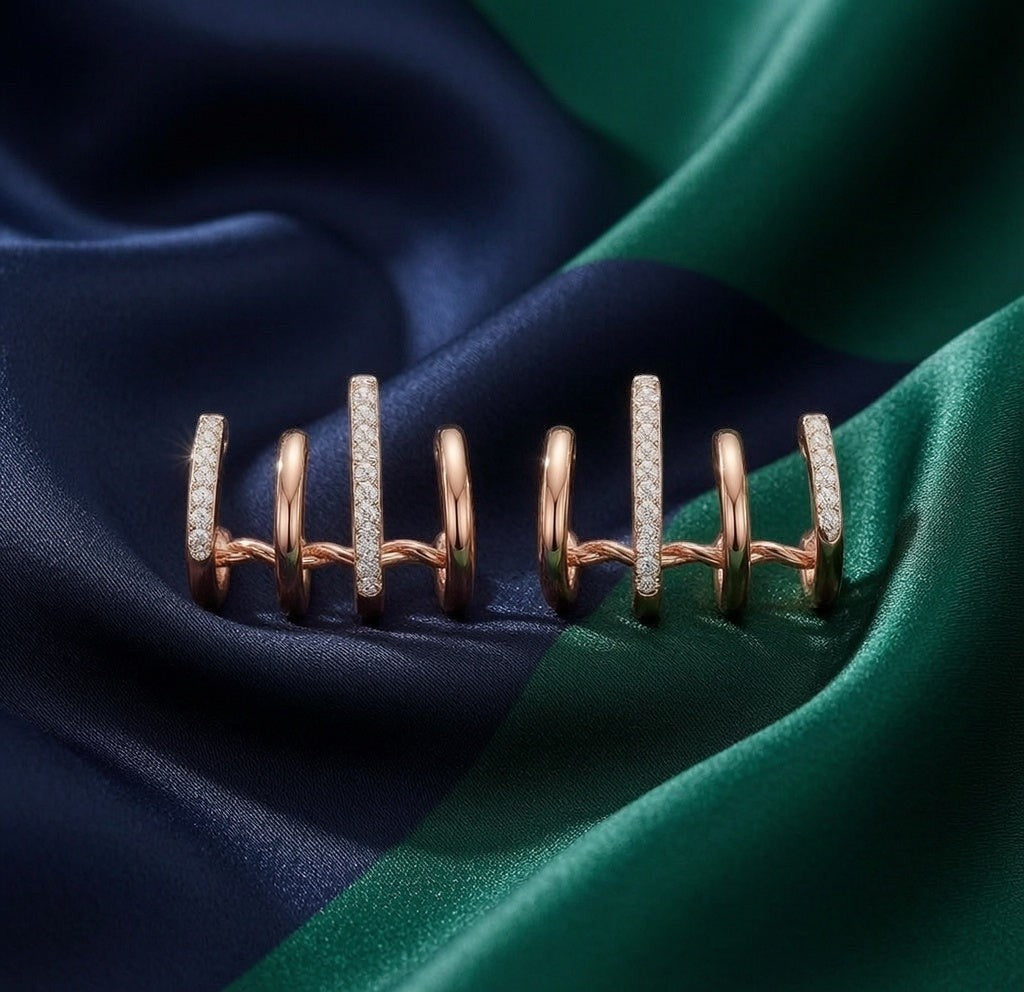 dazzle21 rose gold claw-style earrings with cubic zirconia accents on a dark blue and green silk fabric background